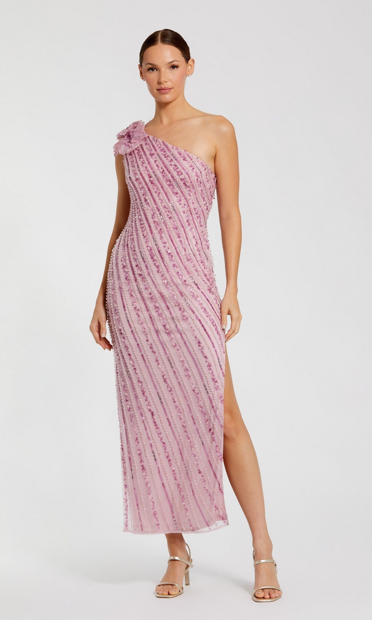 A woman wears the Mac Duggal 94221 long formal dress in orchid—an elegant one-shoulder, sequined beaded mesh midi with a side slit and floral detail—paired with silver high-heeled sandals.